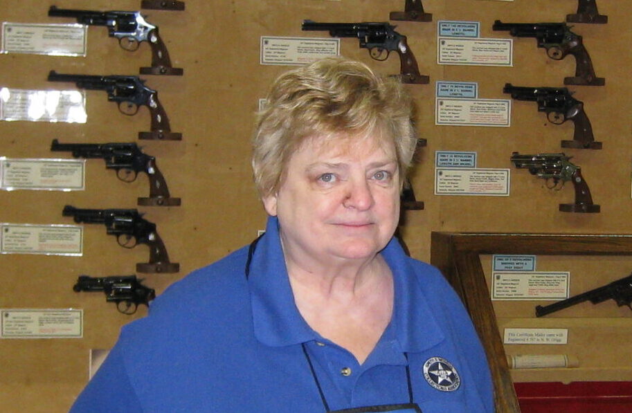 Smith & Wesson Historical Foundation founder standing in front of wall of historic Smith & Wesson firearms